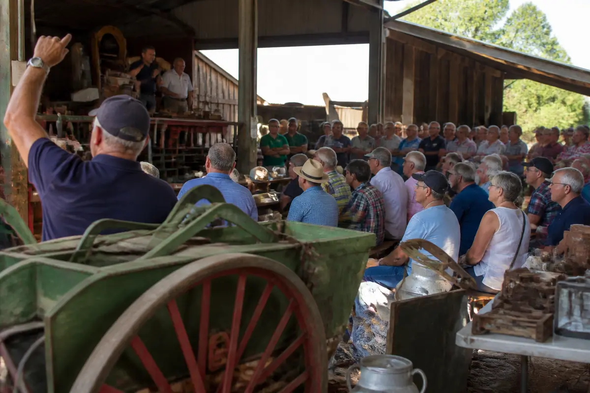 People attending a lively auction in The Dalles barn with raised hand bids