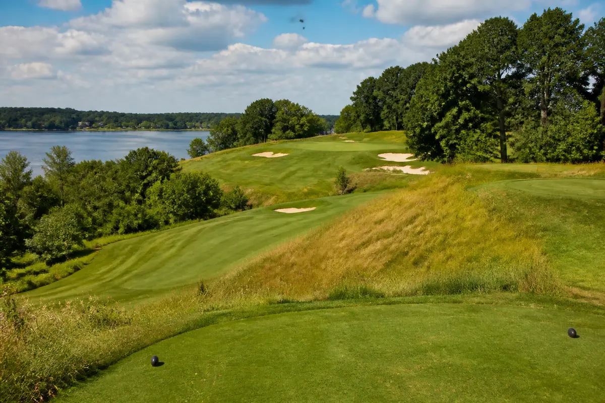 Scenic view of Naga-Waukee Golf Course featuring lush greenery, sand traps, and a lake