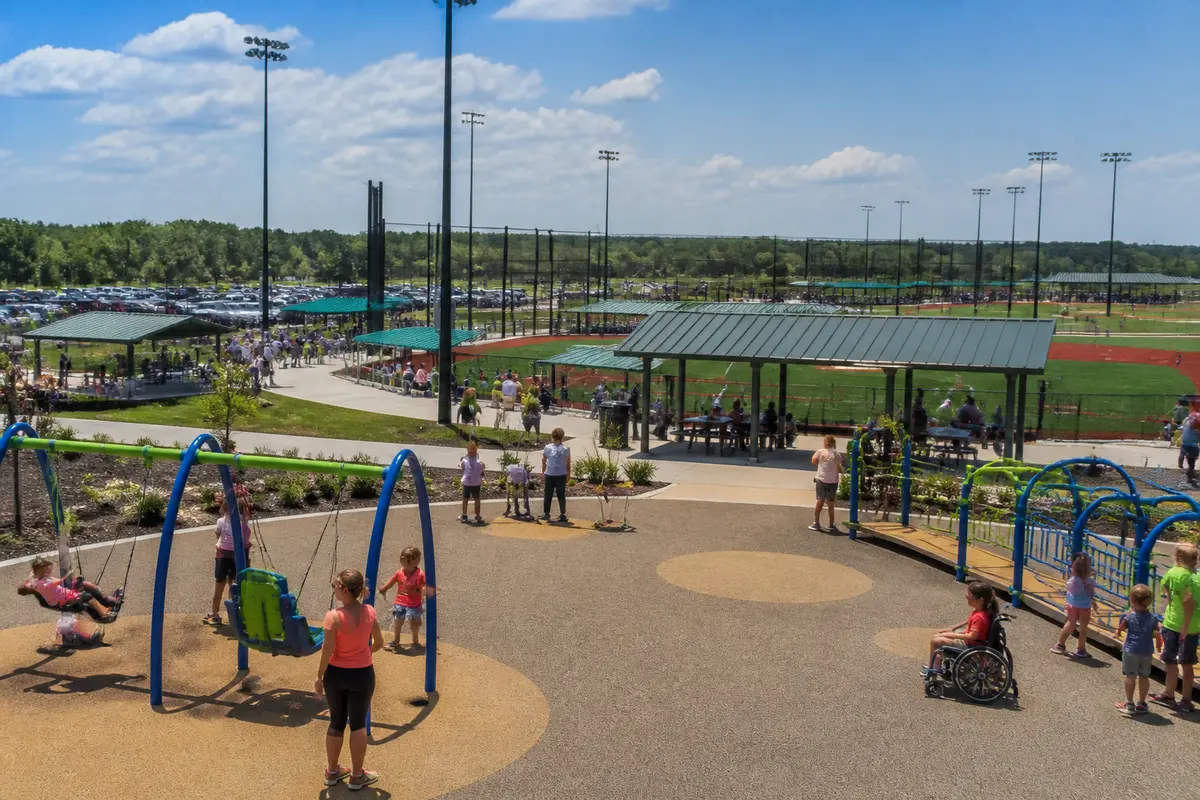 Families enjoying playground and fields at Pewaukee Sports Complex on a sunny day
