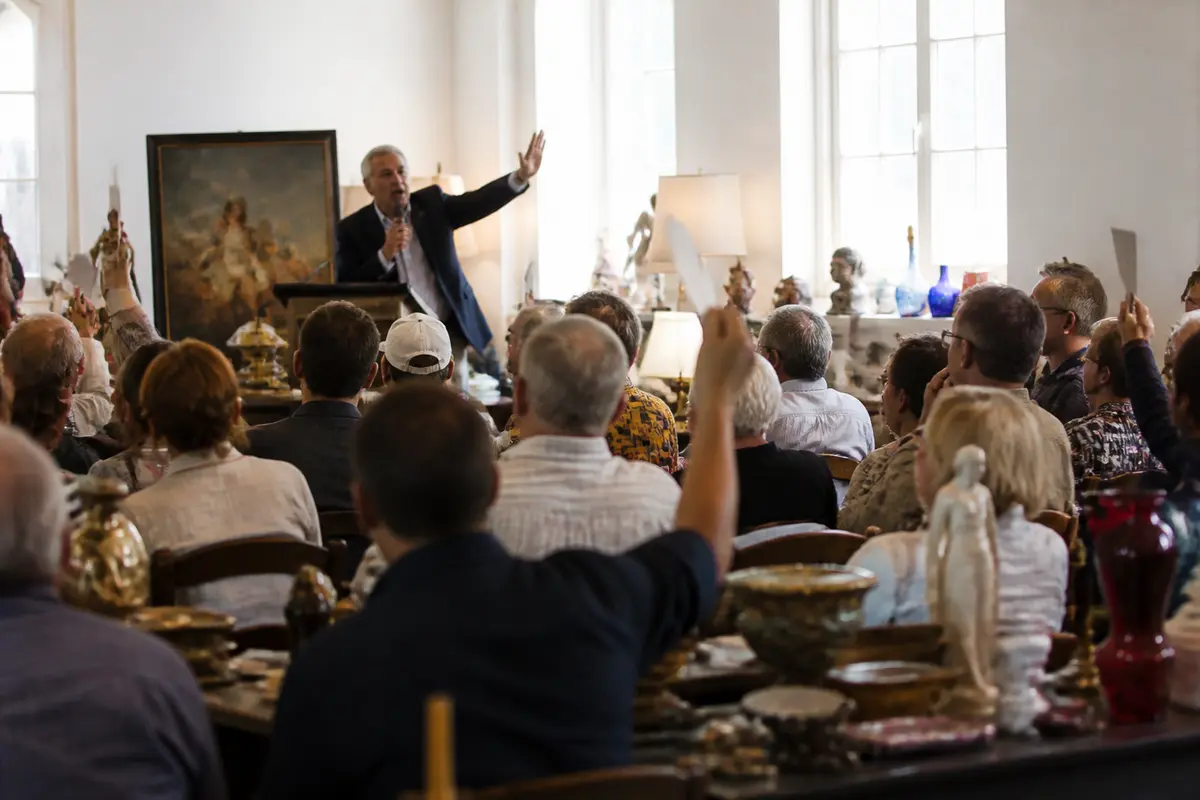 Auctioneer engaging audience at Stafford auction, participants bidding enthusiastically in crowded room